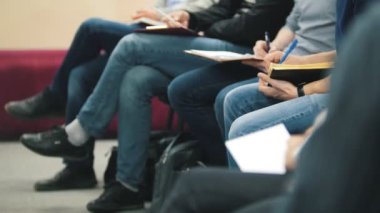 Oturan insanlar ve dinle konferans veya sunum, atölye, sınıf - bacakları ve kolları usta