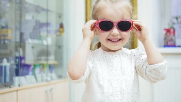 Mała dziewczyna próbuje medyczny moda okulary i śmiejąc się na kamery — Wideo stockowe