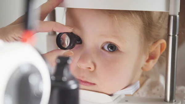 Офтальмология детей - врач-оптометрист проверяет зрение для маленькой девочки — стоковое фото