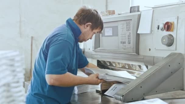 Чоловік працює з різальною гільйотинною машиною на поліграфічному заводі - типографія — стокове відео