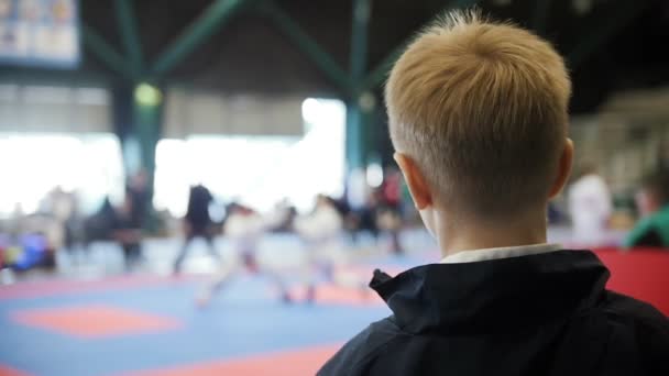 Widz - nastolatek chłopiec ogląda walki karate - Mistrzostwa karate w konkurencji — Wideo stockowe