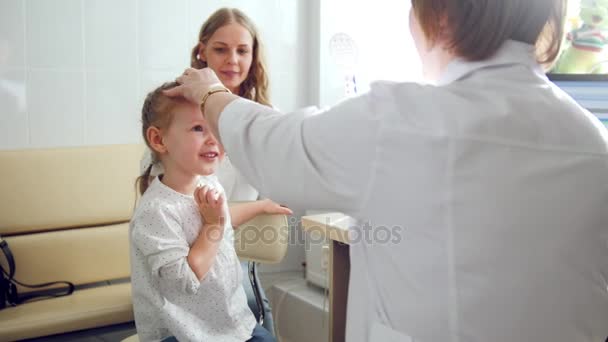 Nettes blondes Mädchen mit Mama in der Kinderaugenheilkunde - Augenoptiker Diagnose Sehkraft — Stockvideo