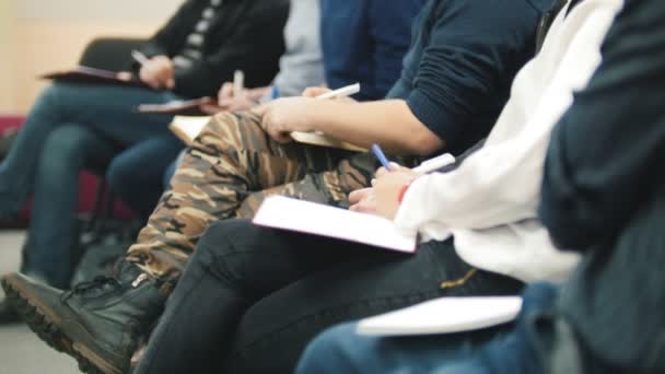 Espectadores en la presentación - empresarios en una conferencia o presentación, taller, clase magistral - bolígrafos y cuadernos en la mano, de cerca — Vídeos de Stock