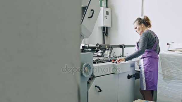 Una trabajadora completa un papel para una revista: trabajo manual en el proceso de impresión del polígrafo — Vídeos de Stock