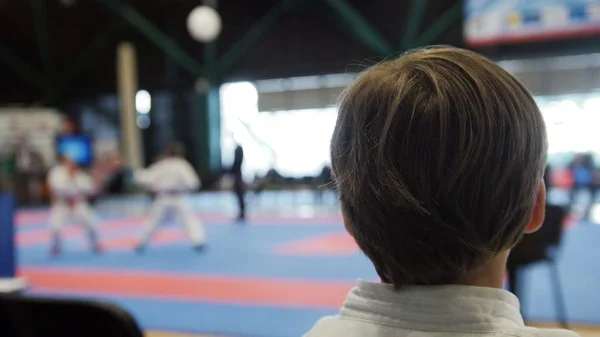 Karate konkurrens - tonåring pojkar tittar på striderna på tatami arena — Stockfoto