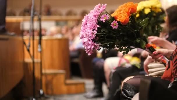 Publikum v koncertním sále drží květiny a tleskají výkon na jevišti — Stock video