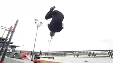 Ücretsiz run - izleyici sarışın adam bir flip Park, parkour atlar.
