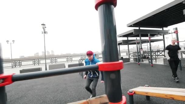 Trazador adolescente saltando en terrenos deportivos - realizar un volteo hacia atrás, cámara lenta — Vídeos de Stock