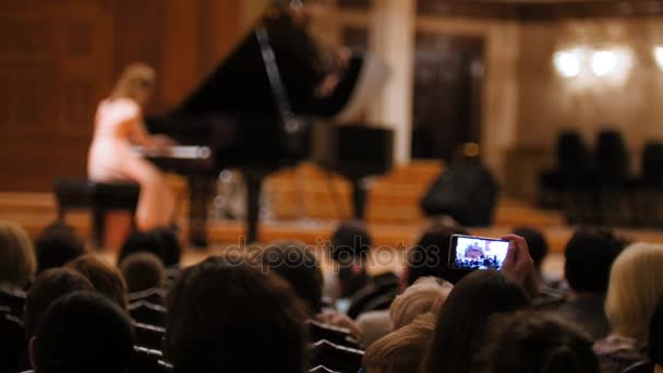 Audience in concert hall during performing piano girl- people shooting performance on smartphone, music opera — Stock Video