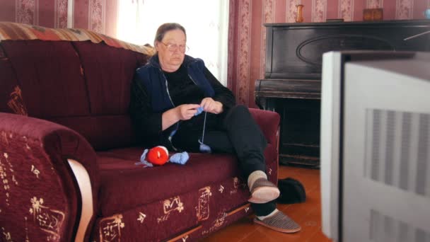 Porträt einer Seniorin, die im Fernsehen Wollsocken strickt — Stockvideo