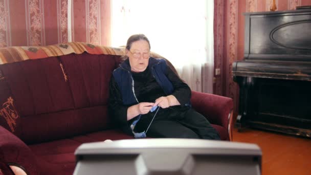 Alte Dame zu Hause - Seniorin schaut fern und strickt Wollsocken — Stockvideo