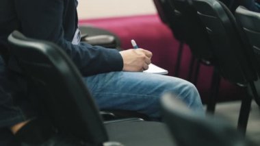 Öğrenci oditoryum kalemle, not defterinde yazıyor yakın çekim