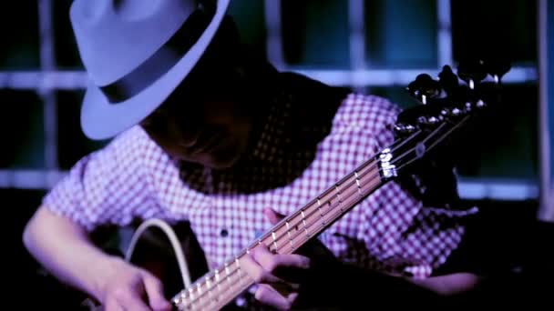 Музыкант в ночном клубе гитарист играет на бас-гитаре, крупным планом — стоковое видео