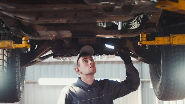Car service - a mechanic checks the suspension of SUV