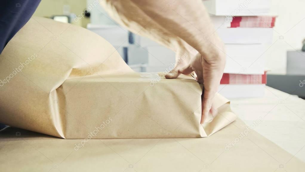 Mans hands packing boxes of sellotape in printing industry