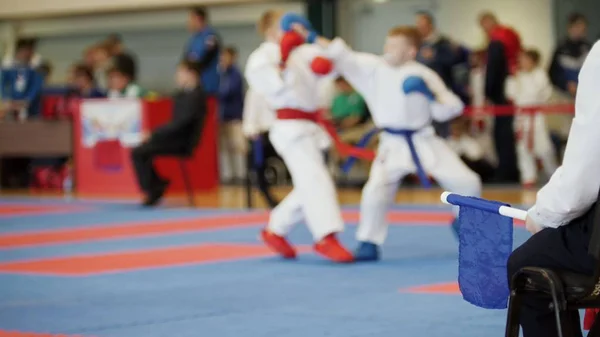 Змагання з бойового мистецтва - тренер-суддя з синім прапором, який дивиться на боротьбу карате підлітків — стокове фото