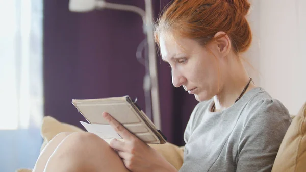 Mädchen zu Hause arbeitet mit Gadget und Notizbuch am Sofa — Stockfoto