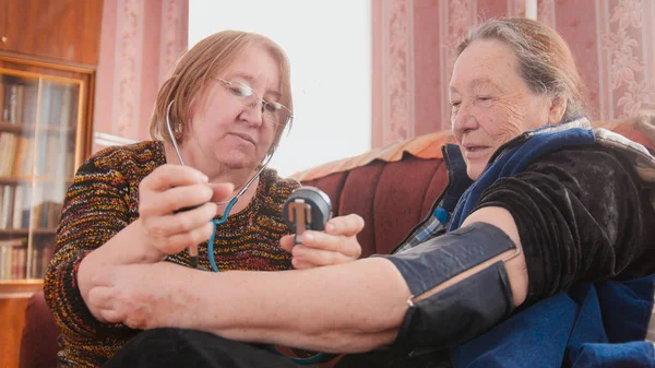 Два пенсионера - проверка состояния здоровья с помощью манометра - измеряют давление, пенсионеры здравоохранения — стоковое фото