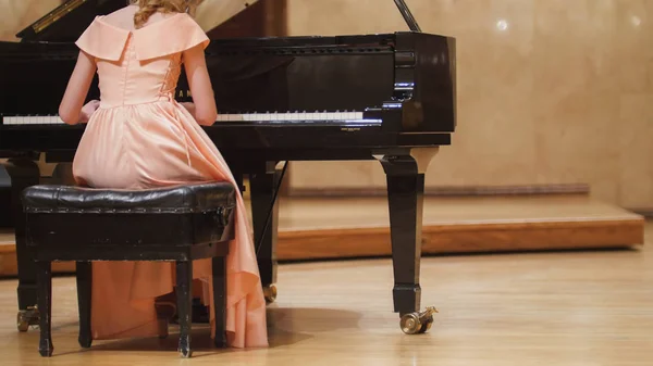 Vista de cerca de la linda adolescente toca el piano en la sala de conciertos en la escena — Foto de Stock