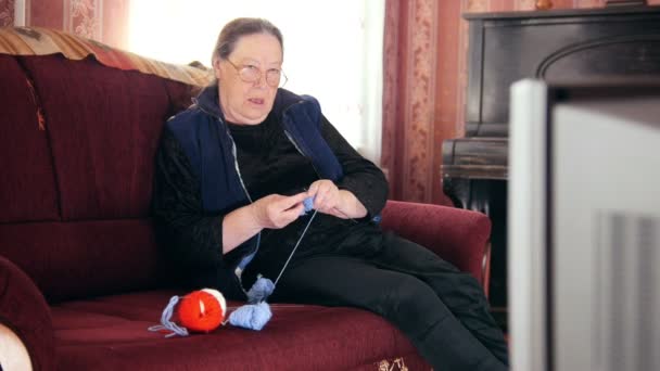 Alte Dame zu Hause - Seniorin schaut fern und strickt Wollsocken — Stockvideo