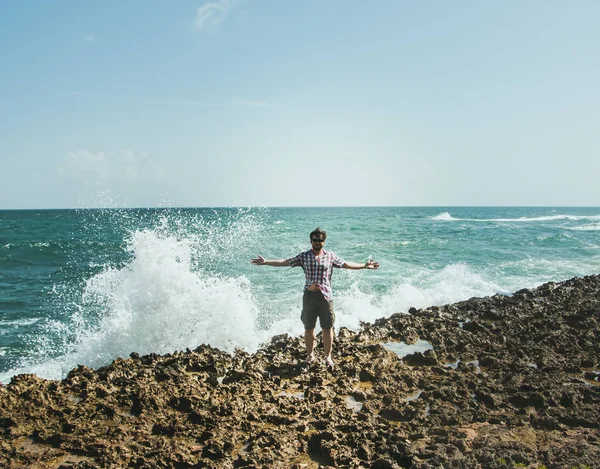 Чоловік в сонцезахисних окулярах стоїть на березі в розпилювачі від аварійних хвиль — стокове фото