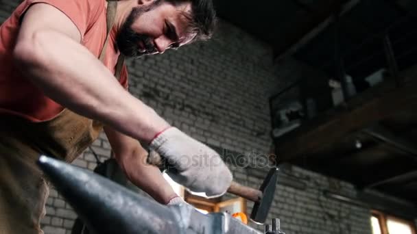 Кузнец с молотком в кузнице создает стальной нож — стоковое видео