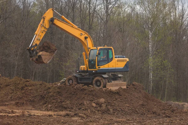 Orange excavator at work - road construction for new highway