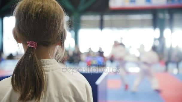 Adolescente karatê esportes menina olhando para lutar no tatami - espectador - câmera lenta — Vídeo de Stock