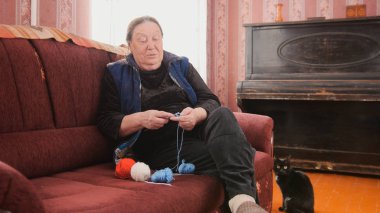 Yaşlı kadın iğneler üzerinde döngüler toplayıp-yün bir örme
