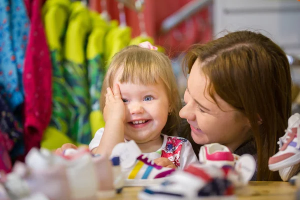 Madre y su hijita compran zapatos en una tienda infantil — Foto de Stock