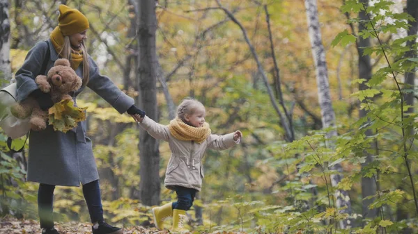 Hijita con su mamá y el oso Taddy pasea en el parque de otoño - juega las hojas — Foto de Stock