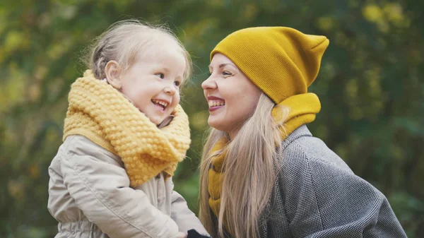 Beetje blonde meisje met haar mama in herfst park - spelen en handen klappen, close-up — Stockfoto