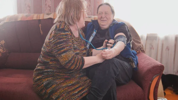 O vizinho mede a pressão arterial das mulheres idosas — Fotografia de Stock