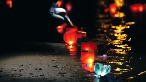 Drijvende lantaarns verlichting op rivier bij nacht - kust met verlichting — Stockvideo