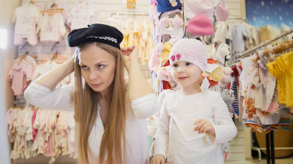 Mamá con hija en la tienda de niños - lleva una gorra negra — Foto de Stock