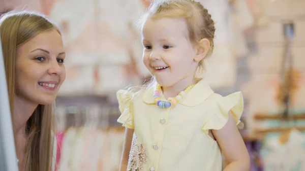 Una chica se admira en el espejo en la tienda de ropa para niños — Foto de Stock