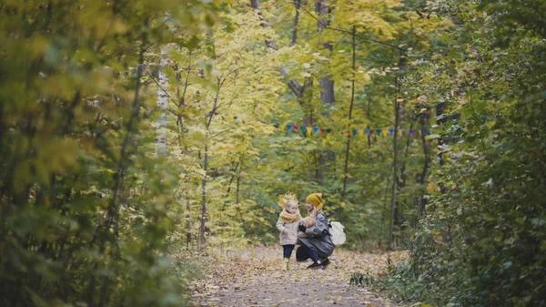 Niña con su madre y el oso de peluche caminando en el parque de otoño — Foto de Stock