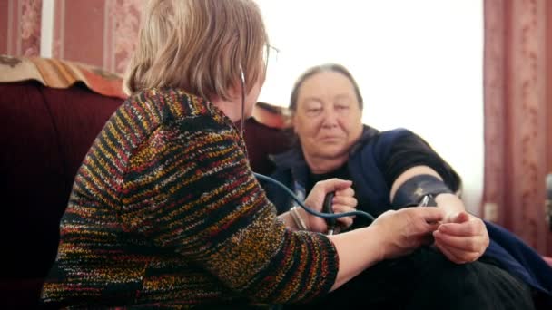 Mujeres pensionistas - comprobación del estado de salud con manómetro - medidas de presión, pensionistas atención sanitaria — Vídeo de stock