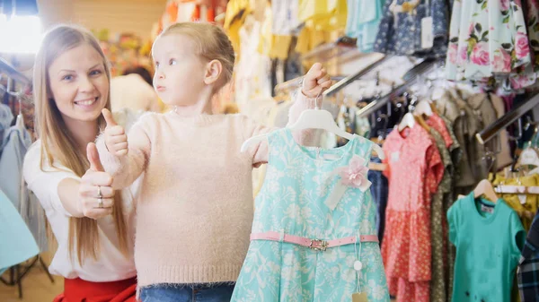 Anya és vele a kis lányom vesz egy kék nyári ruha — Stock Fotó