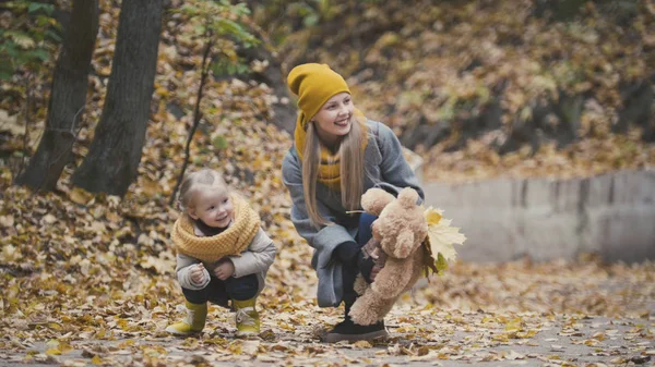 Beetje blonde meisje met haar mama in herfst park - spelen en handen klappen, close-up — Stockfoto