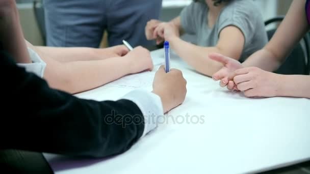 Leerlingen tekenen samen op een groot vel papier — Stockvideo