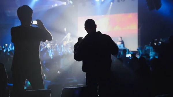 Shadows of people making a video of the concert on a mobile phone