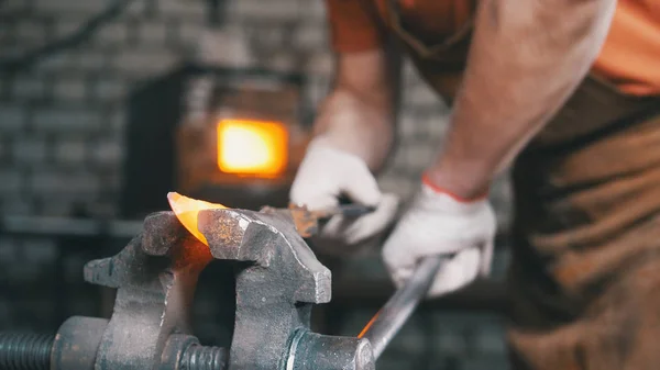 Schmied-Handschuhe greifen nach einem heißen Metallstück — Stockfoto