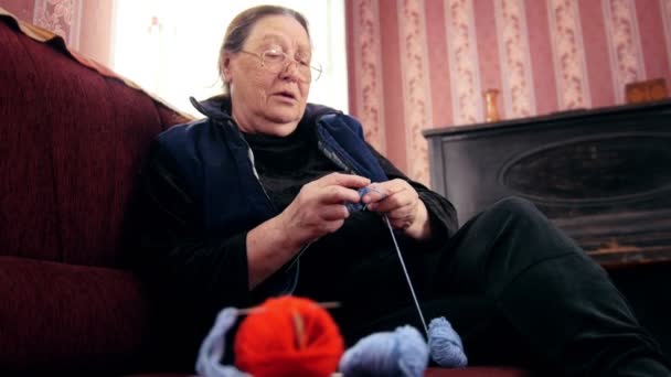 Öreg hölgy haza a kanapé, kötögetni gyapjú zokni — Stock videók