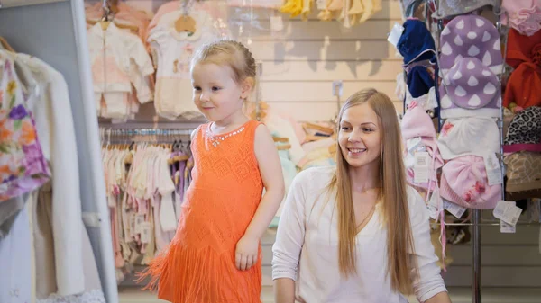 Comprando para niños. La chica admira el espejo en un vestido nuevo — Foto de Stock