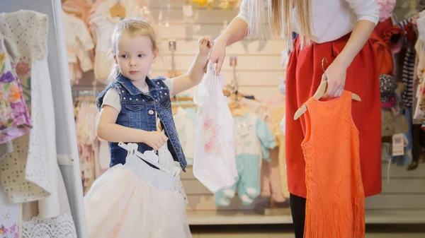 Anya ad neki lánya akasztók ruhát a gyermek ruhaüzlet — Stock Fotó