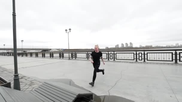 青年杂技-示踪金发碧眼的人跳在公园，跑酷的翻转 — 图库视频影像