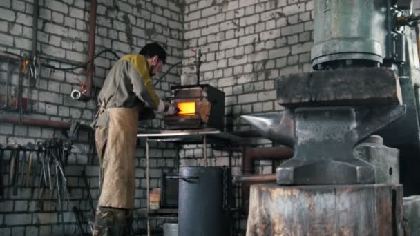 Dans la forge le maître met le détail dans le four — Video