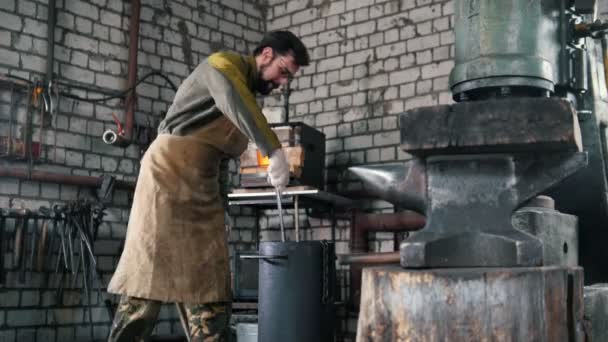 Blacksmith chills the detail in a barrel of engine oil — Stock Video