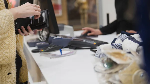 Eine Frau zieht eine Karte aus ihrer Handtasche, um in einem Damenbekleidungsgeschäft zu bezahlen — Stockfoto